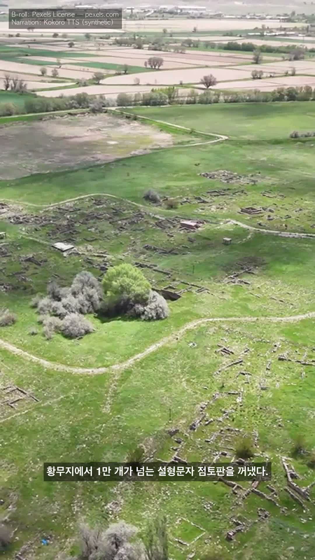 Frame from faceless-hittites-ko-v6: aerial Hattusa archaeological site, Korean caption '황무지에서 1만 개가 넘는 설형문자 점토판을 꺼냈다.' single-line.
